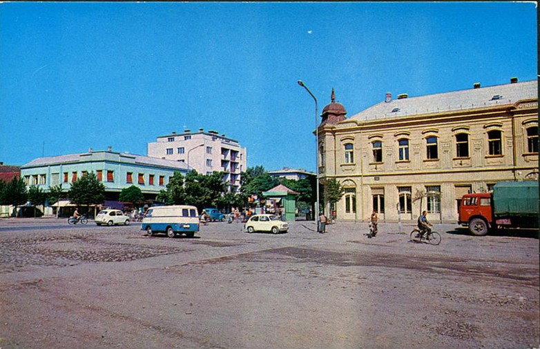 Na staroj fotografiji s druge polovine 20. veka vidi se centar Stare Pazove, zgrada nekadašnje štedionice iz 1905.god., ljudi, automobili itd.